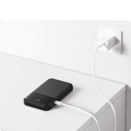 Portable power bank charging via wall socket, eco-friendly off-grid energy solution for sustainable living.