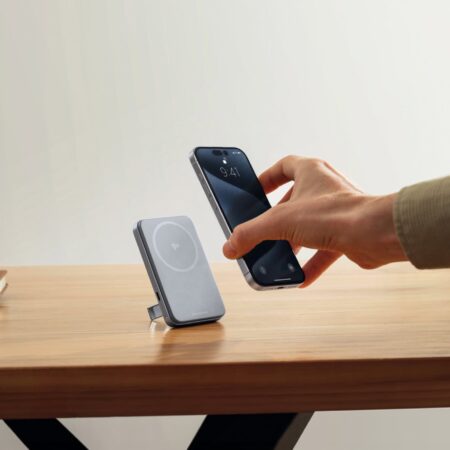 Wireless phone charging pad on wooden desk, compatible with smartphone charging, modern tech accessories, clean workspace, eco-friendly energy solutions.