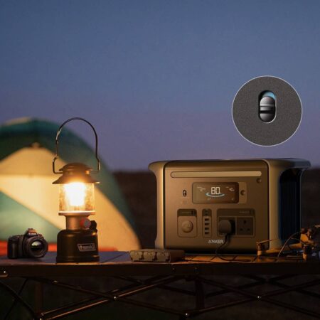 Portable off-grid power station with solar panel, camping lantern, and camera set up outdoors at dusk for outdoor living and renewable energy solutions.